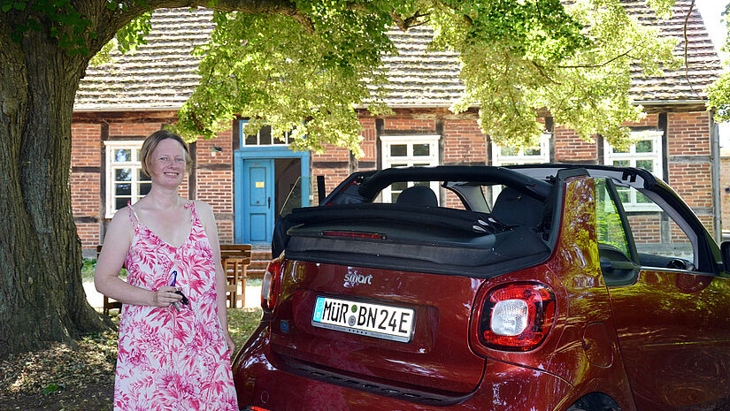 Pastorin Verena Häggberg mit dem e-Auto vor dem Pfarrhaus Vipperow