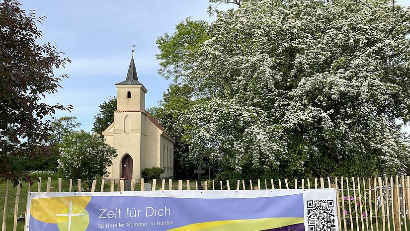 Das Banner der Veranstaltungsreihe "Zeit für Dich - Spiritueller Sommer im Norden" an einer Kirche.