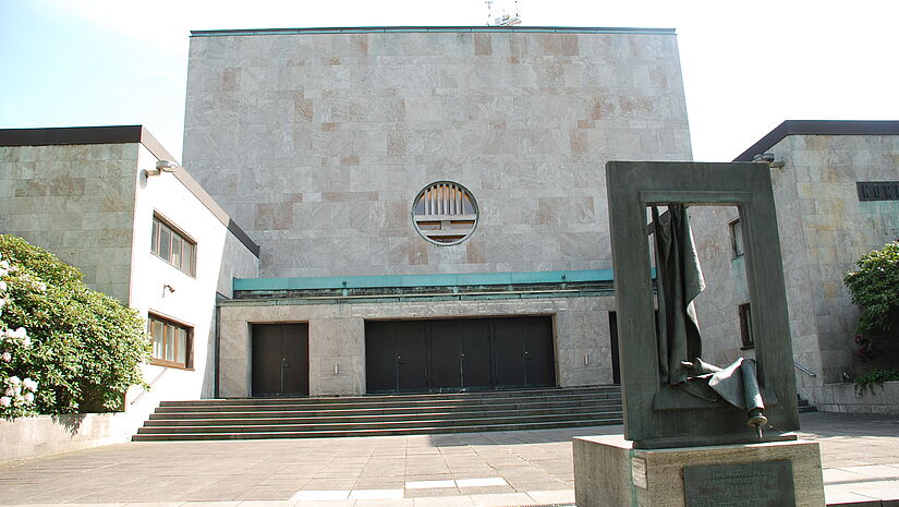 Das Gebäude des einstigen Tempels Oberstraße, heute Rolf-Liebermann-Studio des NDR. Im Vordergrund das Denkmal von Doris Waschk-Balz: Vorhang des Toraschreins mit heruntergefallener Torarolle.