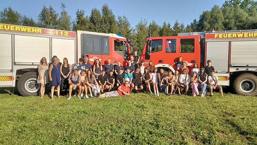 Jugendliche vor zwei Feuerwehrwagen