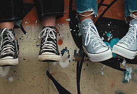 Zwei Paar Füße in Converse-Schnürschuhen