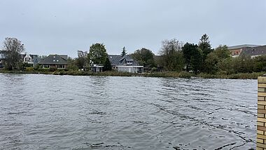 Blick über eine Wasserfläche mit zwei angetriebenen Hausbooten bei der Überschwemmung 2023