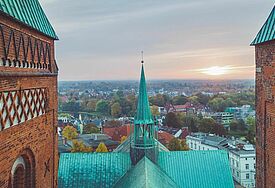 Zwischen den Backsteintürmen des Lübecker Doms blickt man über das Kupferdach über die Hansestadt bis zum Horizont.