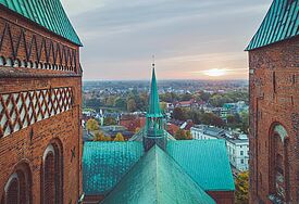 Zwischen den Backsteintürmen des Lübecker Doms blickt man über das Kupferdach über die Hansestadt bis zum Horizont.