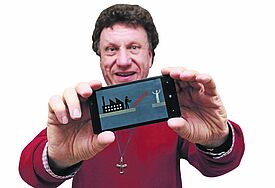Pastor Gunnar Urbach stellt das Logo der Job-App auf seinem Handy vor