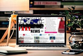 Computer auf einem Schreibtisch, der einen Beitrag zu Fakenews anzeigt