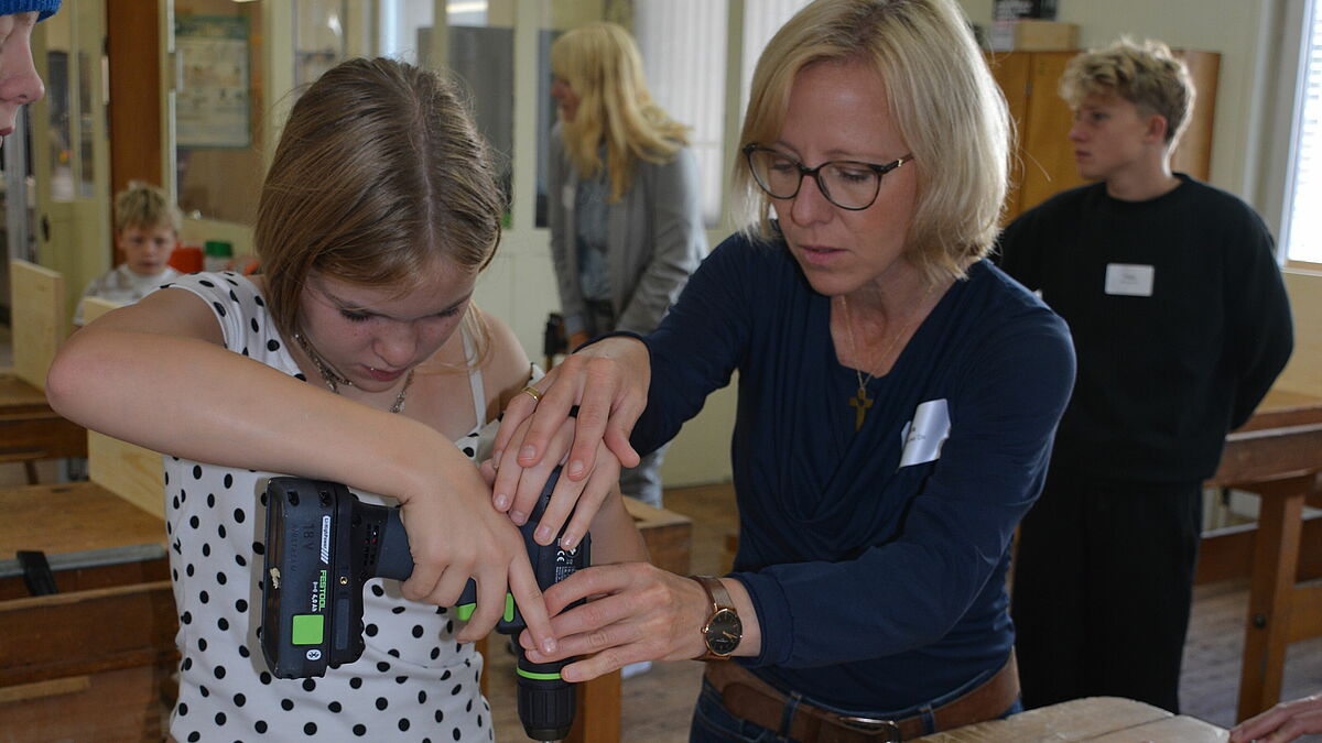Gemeinsam geht es besser: Caro bohrt mit Hilfe von Bischöfin Nora Steen Löcher für den Hocker. @Nordkirche/kw