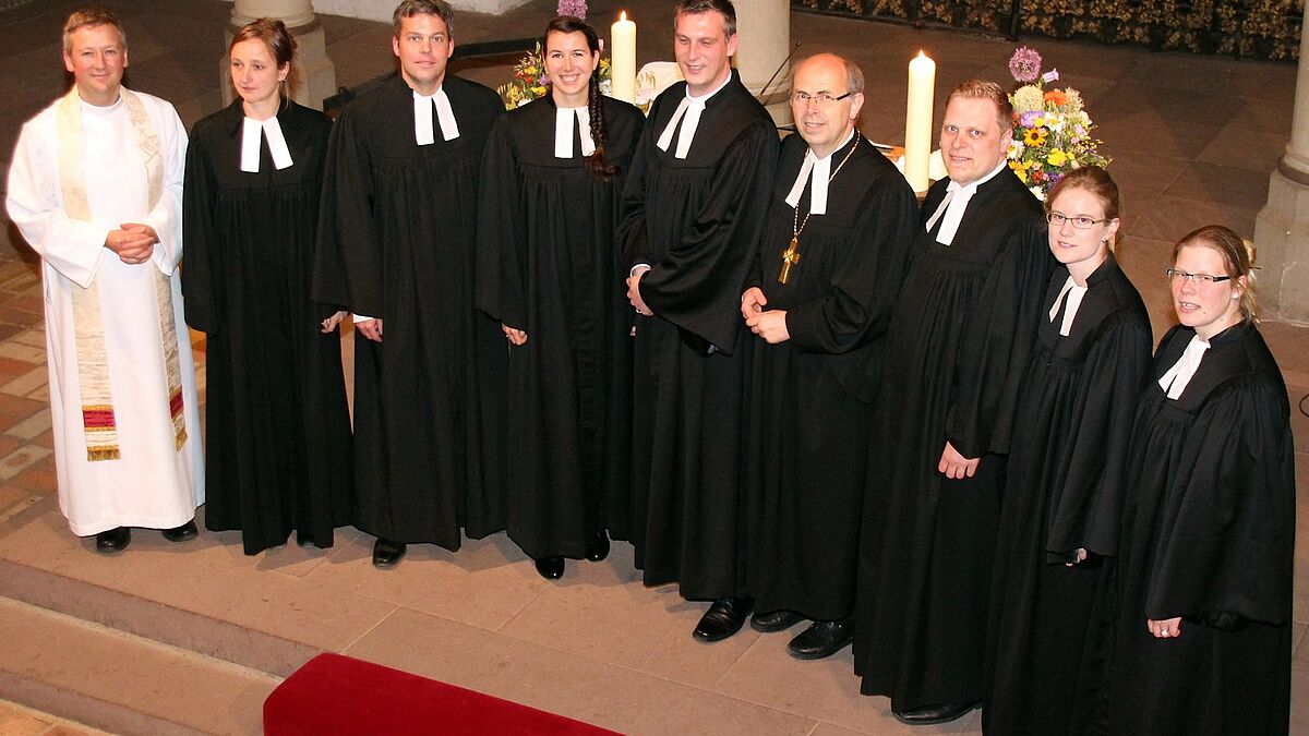 Bischof Magaard (Mitte) und Archdeacon Dr. Alex Hughes aus der Diözese Ely (links) mit den sieben ordinierten Pastorinnen und Pastoren