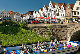 Bootsfahrt auf der zentralen Gracht am Mittelburggraben in Friedrichstadt, Schleswig-Holstein, mit Giebelhäusern am Markplatz. Mit ihren Kanälen, Brücken und Giebeln gleicht Friedrichstadt einer holländischen Idylle.