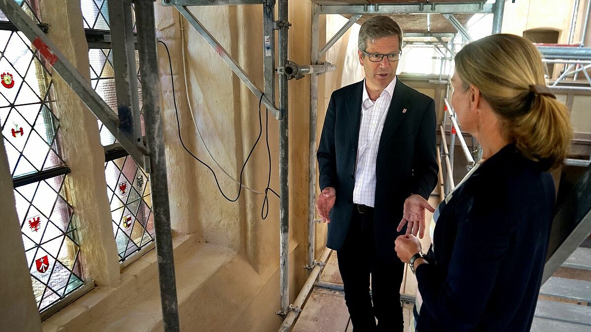 Pastorin Ulrike Streckenbach und Oberbürgermeister Dr. Stefan Fassbinder betrachten das Hansefenster in der Annenkapelle der Greifswalder Marienkirche.