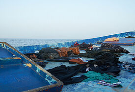 Ein Holzboot mit Kleidung treibt auf dem Mittelmeer.