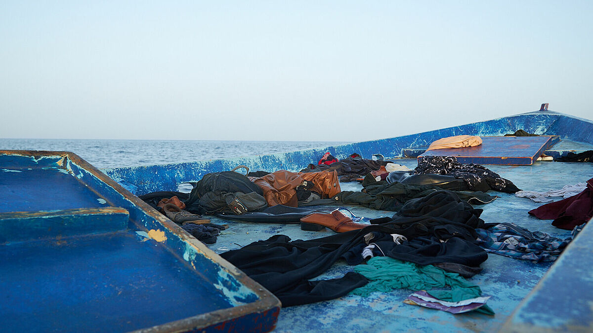 Ein Holzboot mit Kleidung treibt auf dem Mittelmeer.