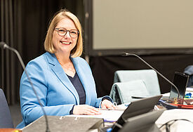 Präses Anja Fährmann sitzt am Laptop und lächelt in. die Kamera.