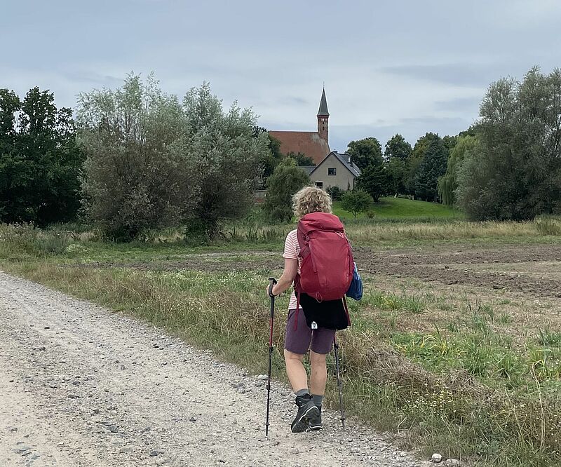 Sandweg mit Pilgerin und dem Kloster Tempzin im Hintergrund