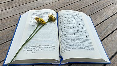 Geh aus mein Herz Lied Gesangbuch auf Holztisch mit Blume