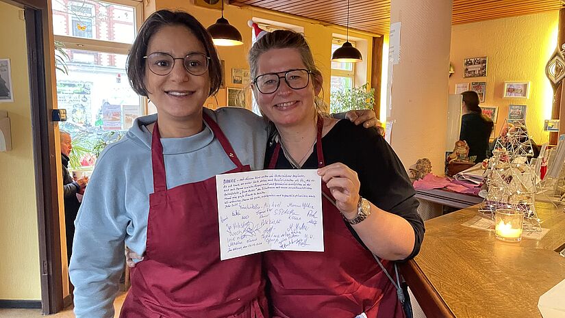 Serpil und Kerstin zwei Frauen halten eine mit Unterschriften beschriebene Klappkarte hoch