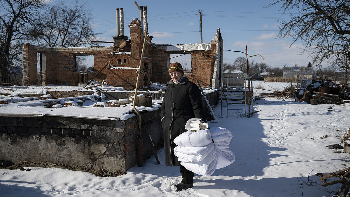Anna Yurchenko zeigt ihr Haus, das zu Beginn des Krieges 2022 in Ivanivka, etwa zwei Autostunden nördlich der Hauptstadt Kiew, von vorrückenden russischen Truppen zerstört wurde. Im Rahmen der Winterhilfe der Partnerorganisation Vostok SOS erhielt sie und anderen betroffene Bewohner des Ortes unter anderem warme Decken.