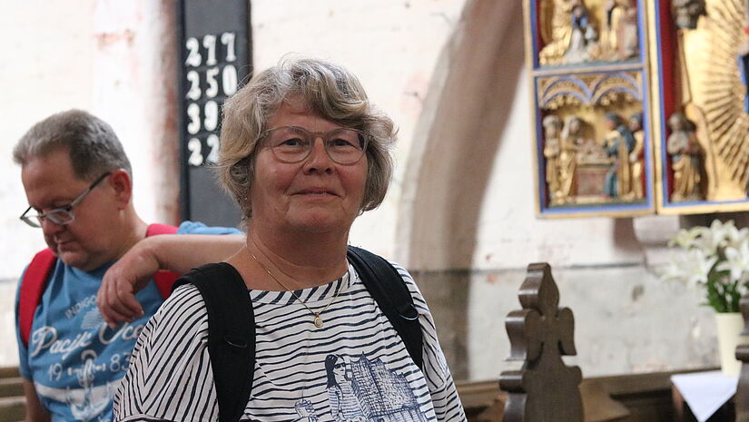 Edith Köpnick steht vor einem Altar in der Dorfkirche auf Poel mit geschnitzter Maria