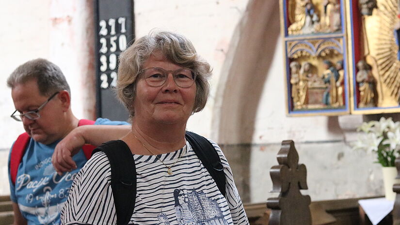 Edith Koepnick Edith Köpnick steht vor einem Altar in der Dorfkirche auf Poel mit geschnitzter Maria