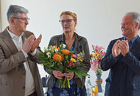 Pröpstin Carstensen mit Blumen. Neben ihr stehen Präses Heydemann und Bischof Jeremias.