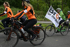 Radler mit Brot für die Welt-Flagge am Rad fahren über eine Landstraße