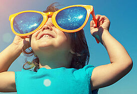fröhliches Kind mit riesiger Sonnenbrille