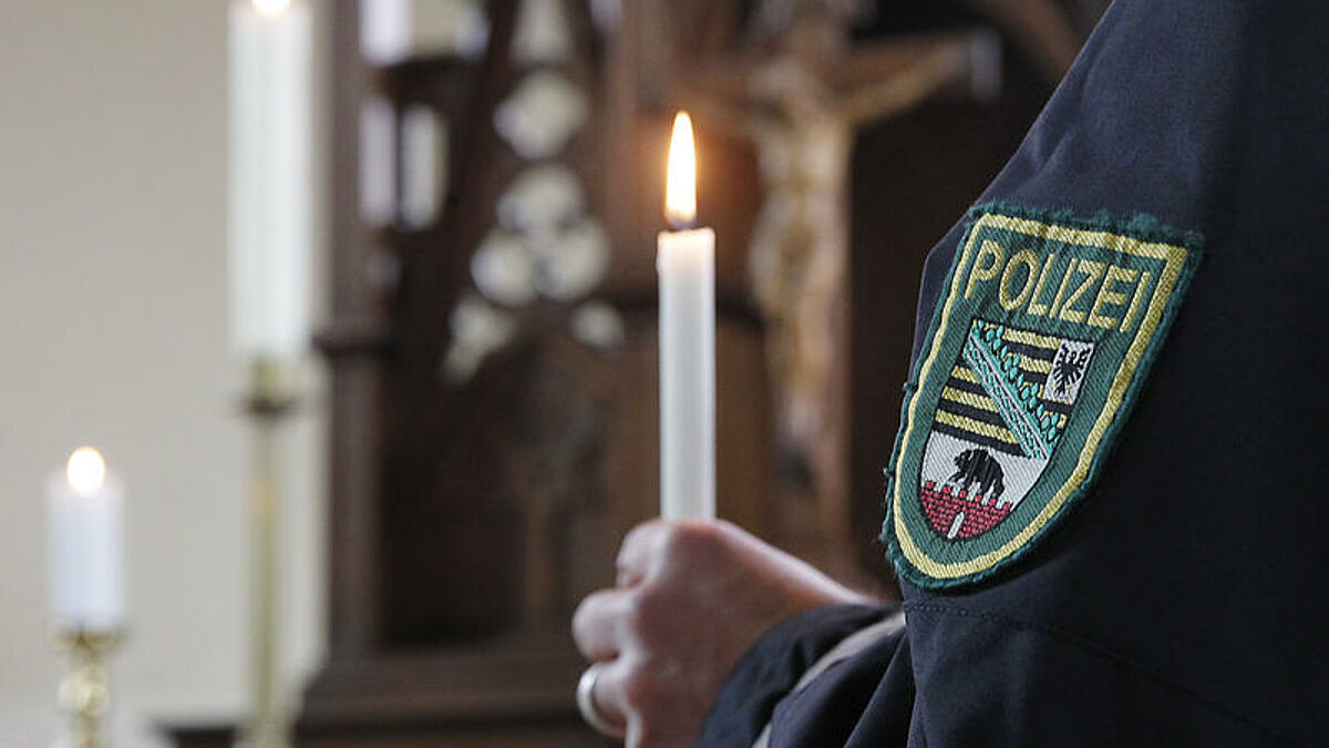 Ein Polizist hält am 24.03.2014 in der ersten Polizeikirche Sachsen-Anhalts in Dessau eine Kerze. Die vermutlich erste Polizeikirche Deutschlands wird am Mittwoch (26.03.14) mit einem Gottesdienst in Dienst genommen. Die Kirche im Dessauer Ortsteil Großkühnau soll vor allem Polizeibeamten als Stätte der Begegnung und Besinnung dienen. Für die Zukunft sind in dem Sakralbau beispielsweise Familientage für Polizisten und ihre Angehörigen geplant. Zudem soll die Kirche offenstehen für Gedenken an im Dienst verstorbene Beamte. Die Backsteinkirche wurde von 1828 bis 1829 im neoromanischen Stil erbaut und ist aus historischen Gründen im Besitz des Landes Sachsen-Anhalt. Die evangelische Gemeinde hat ein Nutzungsrecht. 