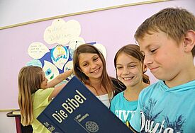 Schüler einer Evangelischen Schule schauen gemeinsam in die Bibel