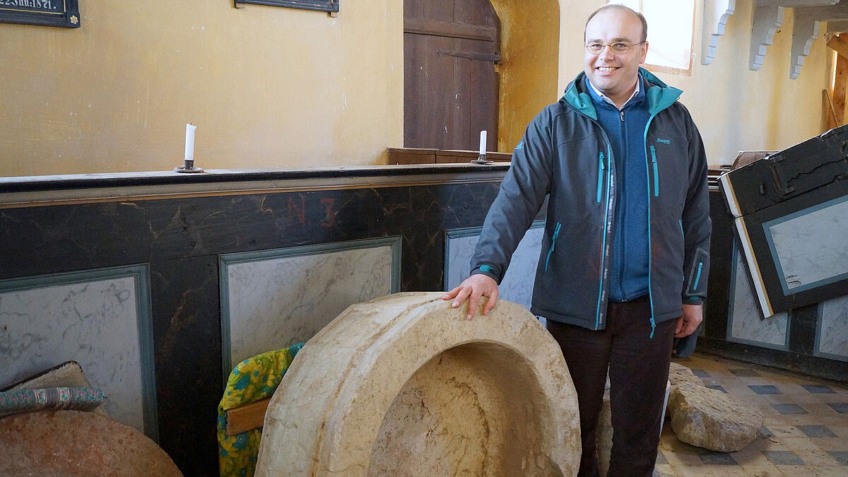 Große Freude über den sensationellen Fund: Pastor Philipp Staak mit dem kürzlich in der Boldekower Kirche geborgenen Taufstein