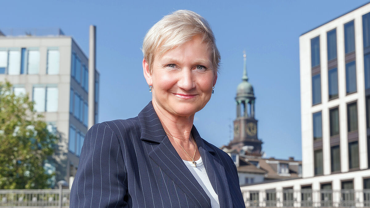 Bischöfin Kirsten Fehrs an den Hamburger Landungsbrücken, in Sichtweite der Turm des Michel.