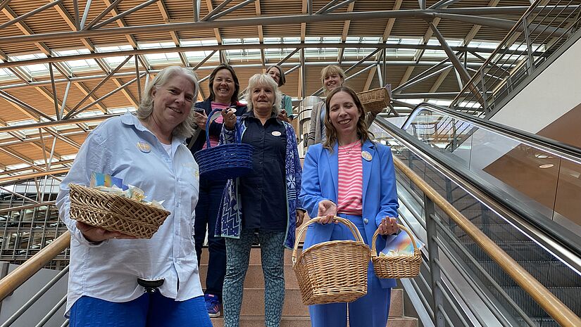 Christina Stemmann und Doris Hamer mit Team auf Rolltreppe am Flughafen Hamburg
