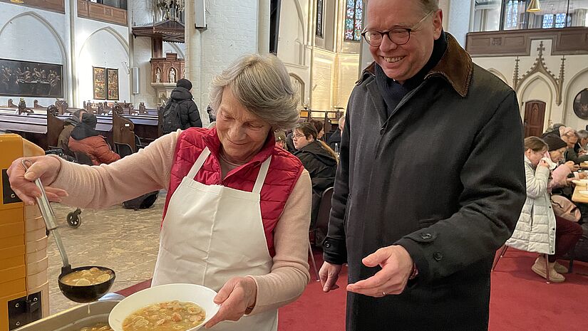 Ehrenamtliche Renate Schöning und Pastor Jens-Martin Kruse beim Servieren der Suppe