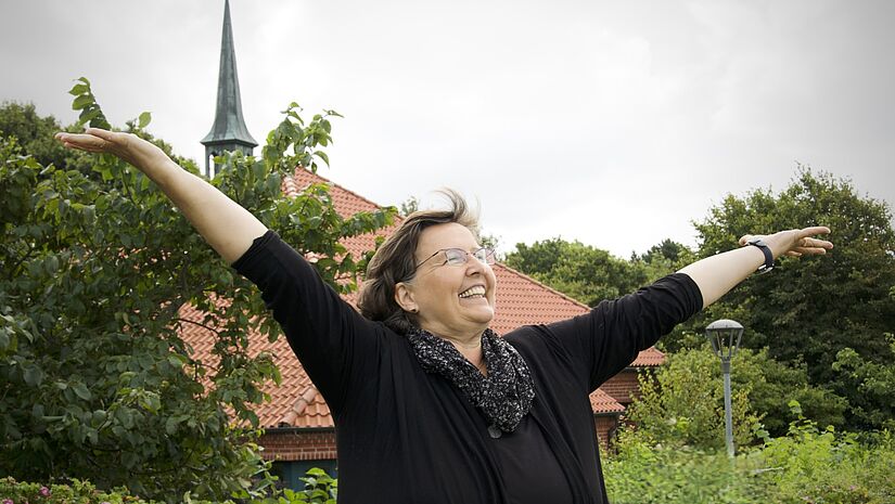 Porträts Andrea Streubier vor evangelischem Familienzentrum Porträts Andrea Streubier vor evangelischem Familienzentrum mit ausgebreiteten Armen