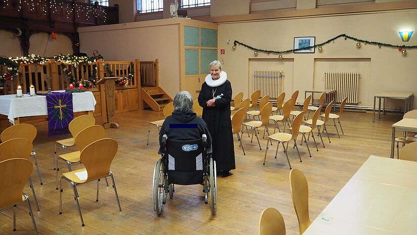 Bischöfin Fehrs spricht vor dem Gottesdienst mit einem Gefangenen im Rollstuhl