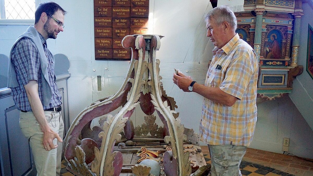 Pastor Dr. Michael Giebel (links) und Küster Karl-Heinz Krause begutachten den am Boden liegenden Schalldeckel der Kanzel, der inzwischen wieder an seinem ursprünglichen Platz angebracht wurde.