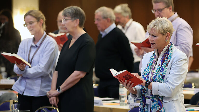 Synodale singen zu Beginn der Sitzung im Plenarsaal ua Blick auf Landesbischöfin und Bischöfin Kirsten Fehrs