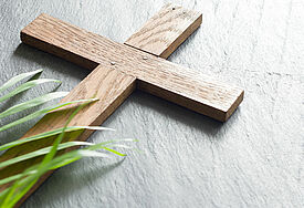 Holzkreuz auf Marmorplatte mit grünem Palmzweig