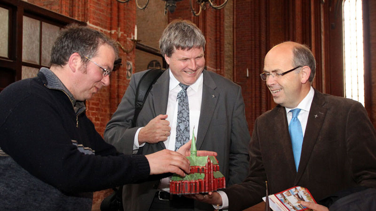 Kantor Martin Poley (St. Nikolai Wismar) zeigt Bischof Dr. Andreas von Maltzahn und Bischofsvertreter Gothard Magaard ein Kirchenmodell zum Anfassen (V.l.n.r.)