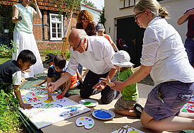 „Tag des Miteinanders“ im Parchimer Haus der Begegnung „M41“ der Kirchengemeinden Parchim St. Marien und Damm am 23. Mai 2017: Gemeinsam mit Kindern einheimischer und geflüchteter Familien malt Landesbischof Ulrich ein Wandbild zum Thema „Frieden“. Das aus mehreren Leinwänden bestehende Gemeinschaftswerk soll künftig die Räume des „M41“ schmücken. Foto: Döbler/Nordkirche