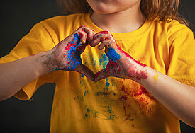 Farbverschmierte Kinderhände, die ein Herz bilden