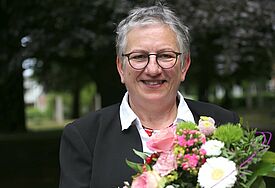 Annegret Wegner-Braun lächelnd mit einem Strauß Blumen