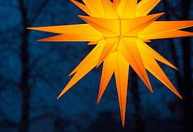 Orangegoldener Herrnhuter Adventsstern vor tiefblauem Nachthimmel