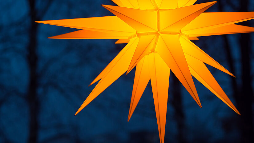 Orangegoldener Herrnhuter Adventsstern vor tiefblauem Nachthimmel