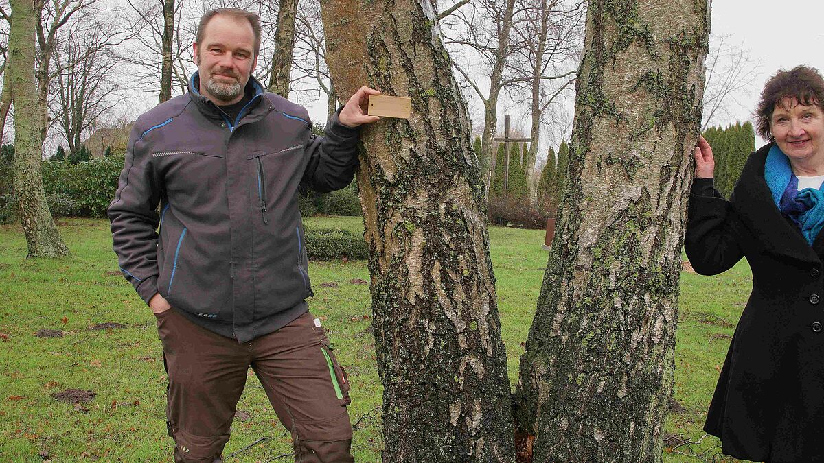 Friedhofsgärtner René Klemm und Pastorin Susanne Petersen zeigen, wie die Namensschilder am Baumgrab aussehen. 