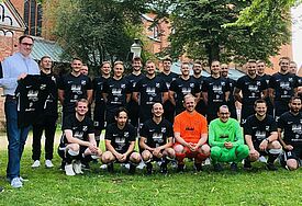 Trainer André Guhlke, Bürgermeister Jan LIndenau (1. Und 2. V. li.) sowie Dennis Forte, Inhaber von druckfory (re, hockend) und Pastor Martin Klatt präsentieren die neuen T-Shirts der mit den Spielern der 2. Herrenmannschaft des TuS Lübeck von 1893 e. V..