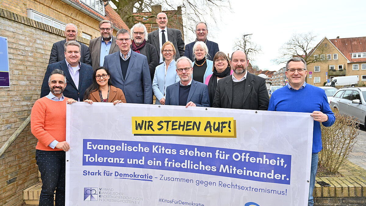 Pröpstinnen und Pröpsten halten gemeinsam mit Bischöfin Nora Steen (Mitte, helle Jacke) und VEK-Geschäftsführer Markus Potten (links daneben) eines der Banner hoch.