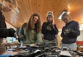 Vier jungen Menschen hinter einem Berg alter Handys