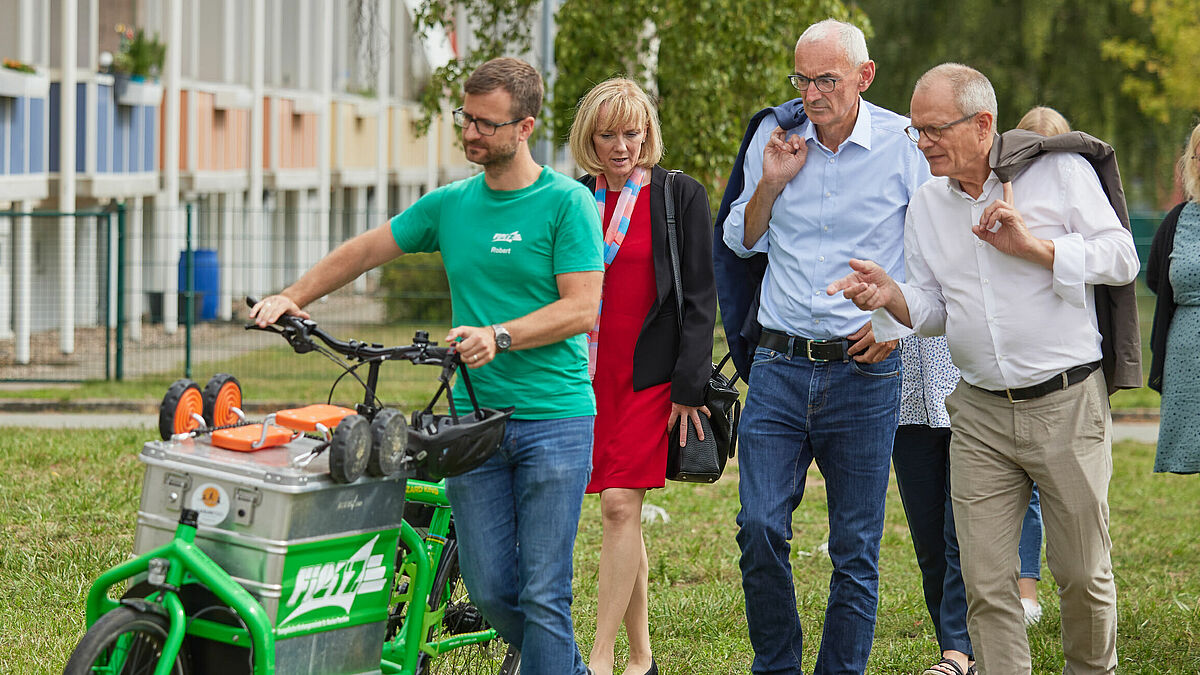 Gemeindepädagoge Robert Stenzel ist mit seinem mobilen Spielzimmer unterwegs. Auf einem Rundgang führt er  Landespastor Paul Philipps (Mitte) und Diakoniepräsident Ulrich Lilie (rechts) durch die Weststadt Parchim. 