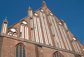Von unten nach oben fotografiert: Backstein-Ostfassade der Kirche St. Marien in Greifswald, der Himmel ist blau