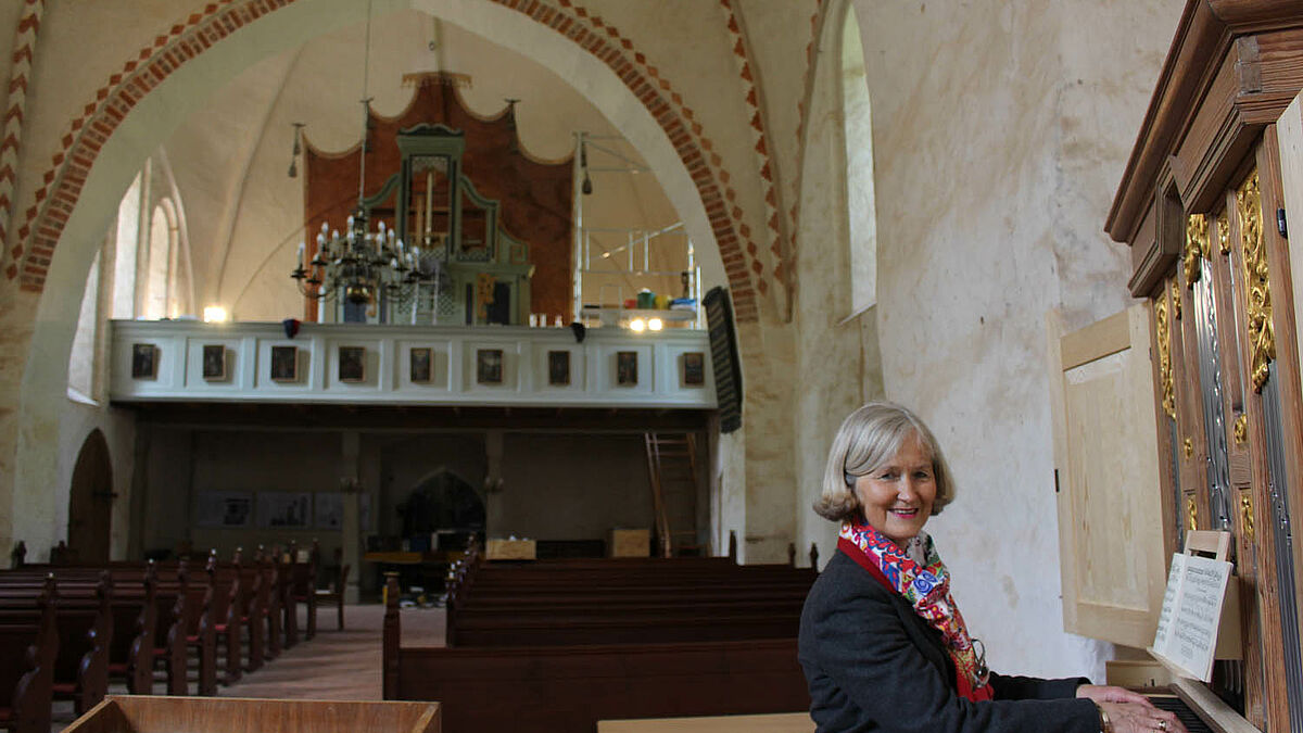 Die Vorsitzende des Fördervereins Stefanie von Laer am Richborn-Positiv im Altarraum der Dorfkirche Ruchow, im Hintergrund auf der Empore die fast fertiggestellte Paul-Schmidt-Orgel.